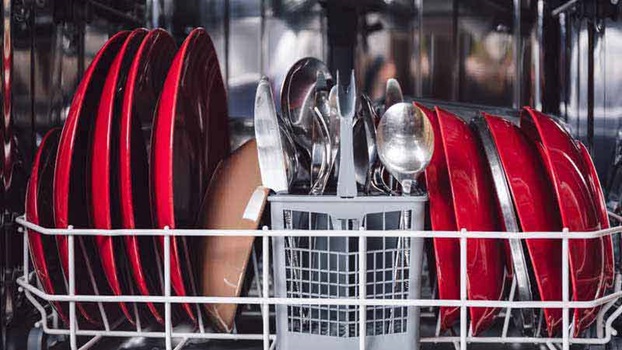 Talheres e pratos vermelhos dentro da máquina de lavar loiça.